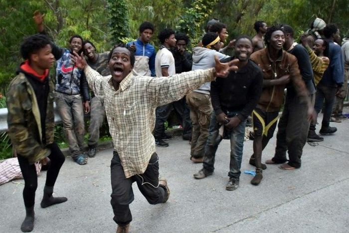 Migrants celebrate after forcing their way through a fence between Morocco and the tiny Spanish enclave of Ceuta, on February 17, 2017