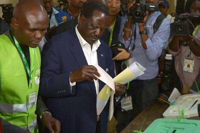 Kenya's opposition alliance, National Super Alliance (NASA) presidential candidate, Raila Odinga prepares to cast his ballots on August 8, 2017 mobbed by a battery of photo journalists at Old-Kibera primary school polling centre, in Nairobi