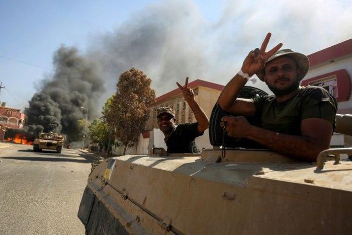 Members of the Iraqi forces flash the victory sign from a tank as they advance through Tal Afar on August 26, 2017