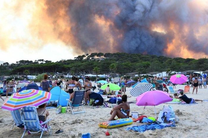 People watch from the beach as smoke billows into the sky over Bormes-les-Mimosas