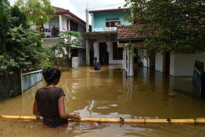Sri Lankan residents make their way through floodwaters in Kaduwela. Emergency teams are rushing to distribute aid to half a million displaced after the island's worst flooding in more than a decade claimed 126 lives and left scores more missing