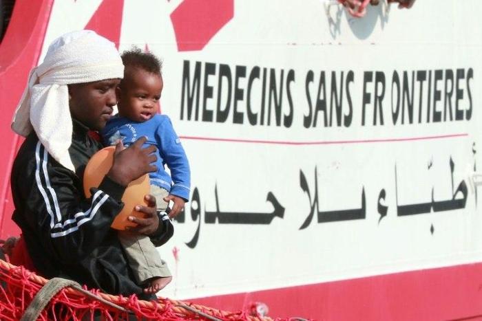 A migrant man carries a child as they disembark from the Italian rescue ship Vos Prudence run by NGO Medecins Sans Frontieres (MSF) as it arrives in the early morning of July 14, 2017, in the port of Salerno carrying 935 migrants, including 16 children...