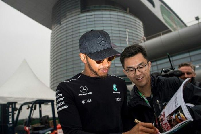 Mercedes' British driver Lewis Hamilton signs an autograph for a Chinese fan in the paddock in Shanghai ahead of the Formula One Chinese Grand Prix