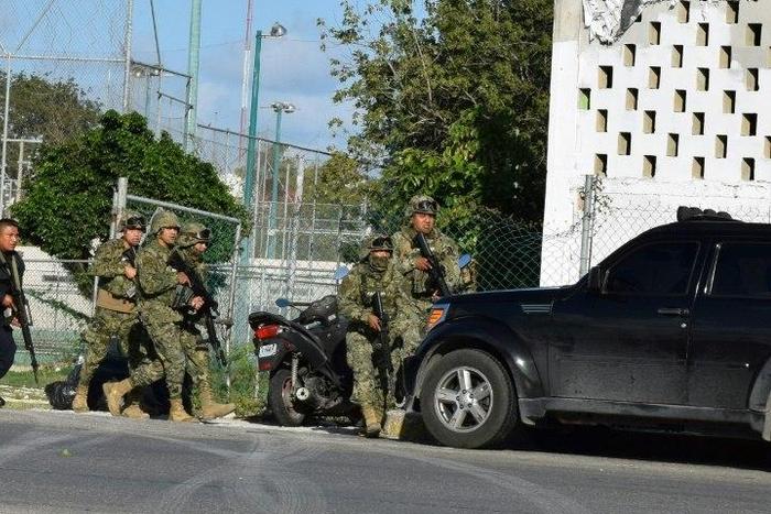 Police and soldiers take cover during an attack by gunmen on the Quintana Roo state prosecutor's office in Cancun, Mexico, which left four people dead
