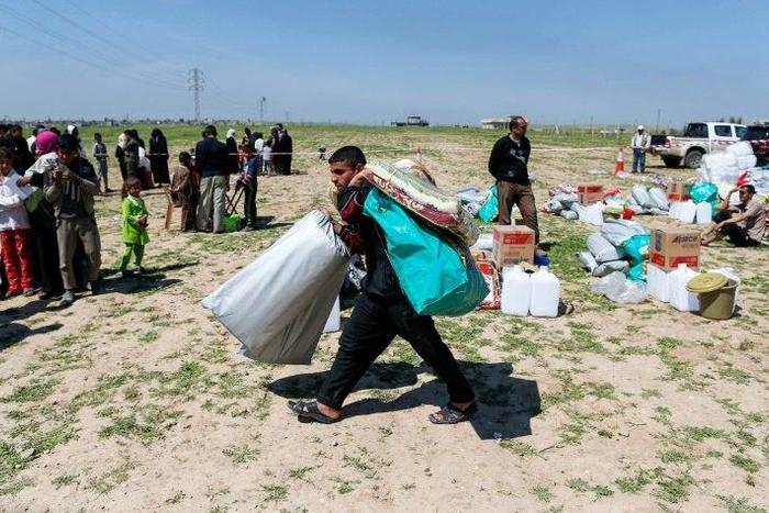 A displaced Iraqi receives humanitarian aid supplies at a camp for the internally displaced, in Salamiyah village east of Mosul, on March 27, 2017