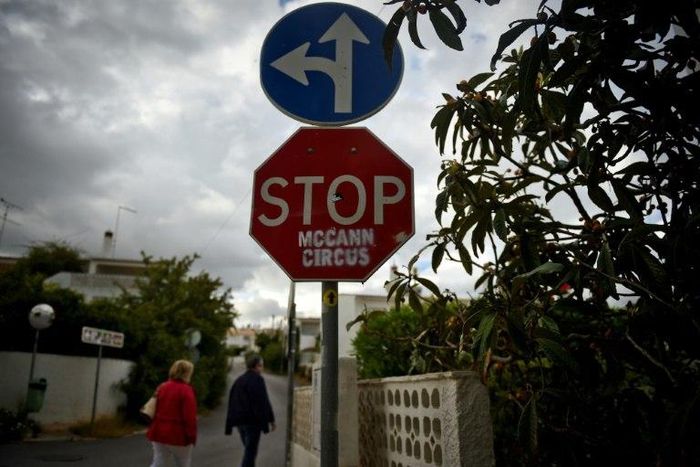 People pass by a stop sign that was vandalised with the message "STOP McCann Circus" in the Portuguese town of Praia da Luz where British girl Madeleine McCann disappeared 10 years ago