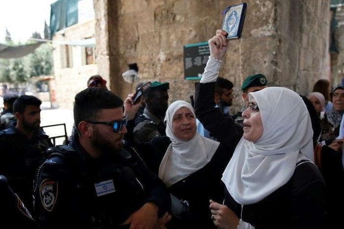 A Palestinian protester holds a copy of the Koran and shouts slogans in front of Israeli security forces during a demonstration in Jerusalem's Old City on July 20, 2017
