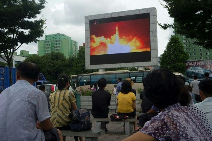 People watch as coverage of an ICBM missile test is displayed on a screen in a public square in Pyongyang on July 29, 2017