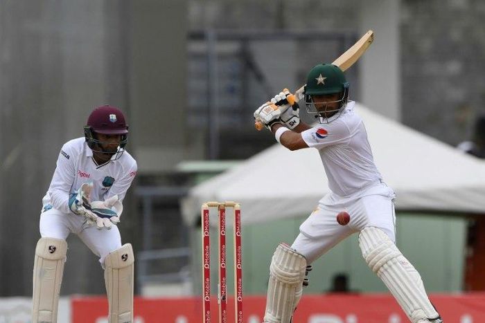 Babar Azam of Pakistan plays a cover shot as West Indies wicketkeeper Shai Hope looks on during the first day of play, of the 3rd and final test match at the Windsor Park Stadium in Roseau, Dominica on May 10, 2017