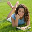 woman reading book on grass