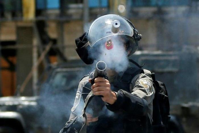 An Israeli border guard fires tear gas at Palestinian protesters near the Jewish settlement of Beit El in the occupied West Bank on July 24, 2017