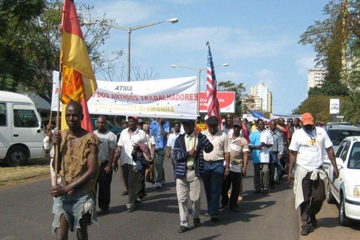 Demonstrators carrying a banner reading "Association of Former Mozambican Workers in Germany" march in Maputo over unpaid wages