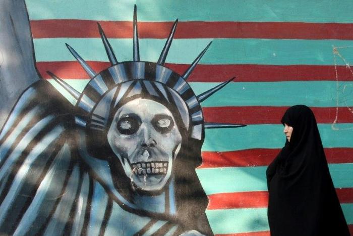 An Iranian woman walks past a mural on the wall of the former US embassy in Tehran