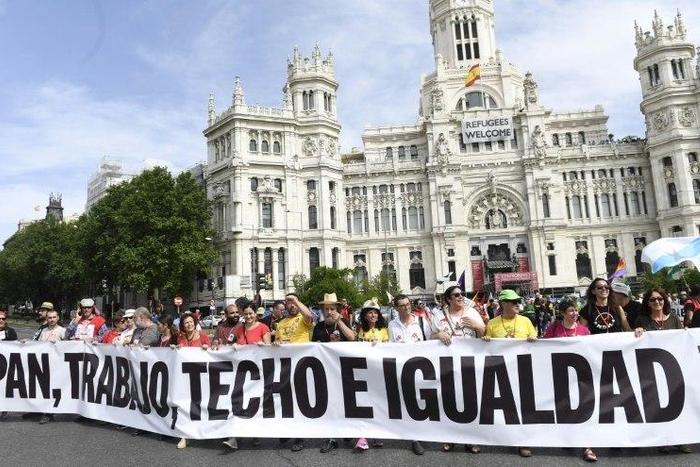 People hold a banner that reads "Bread, work, roof and equality" during a demonstration in Madrid on May 27, 2017 to denounce degraded working conditions