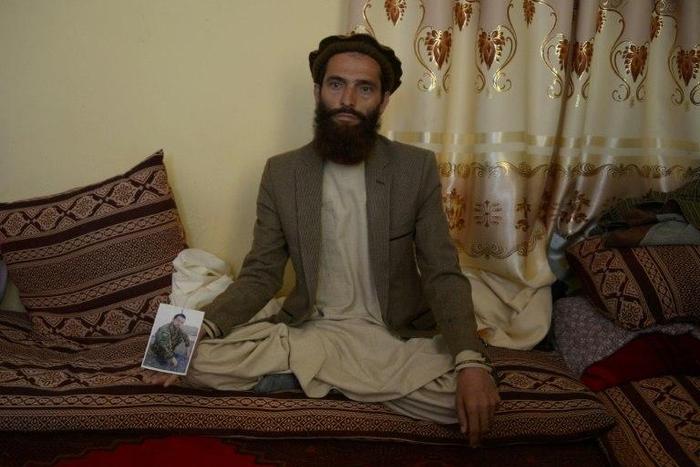 Afghan resident Ahmadullah poses for a photograph on April 24, 2017 with a picture of his brother Shir Mohammad, a soldier killed in a Taliban attack on an army base on the outskirts of Mazar-i- Sharif