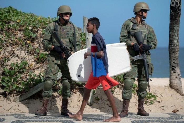 Brazilian soldiers stand guard on Ipanema beach in Rio de Janeiro on July, 29, 2017, following the government decision to deploy some 8,500 troops in the city to fight organized crime and a spike in street violence