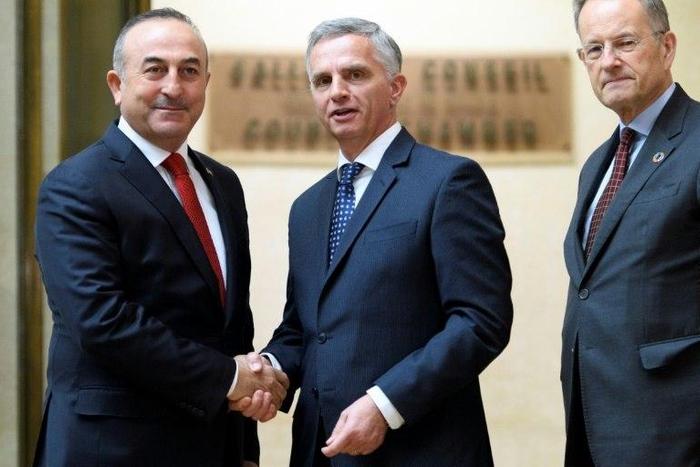 Turkey's Foreign Minister Mevlut Cavusoglu (L) shakes hands with Swiss sounterpart Didier Burkhalter (C) as Director General of the UN Office in Geneva Michael Moller looks at UN headquarters in the Swiss city on January 12, 2017