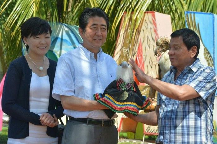 Japanese Prime Minister Shinzo Abe (2nd L) is handed a stuffed Philippine eagle by Philippine President Rodrigo Duterte at a hotel in Davao City, Mindanao on January 13, 2017