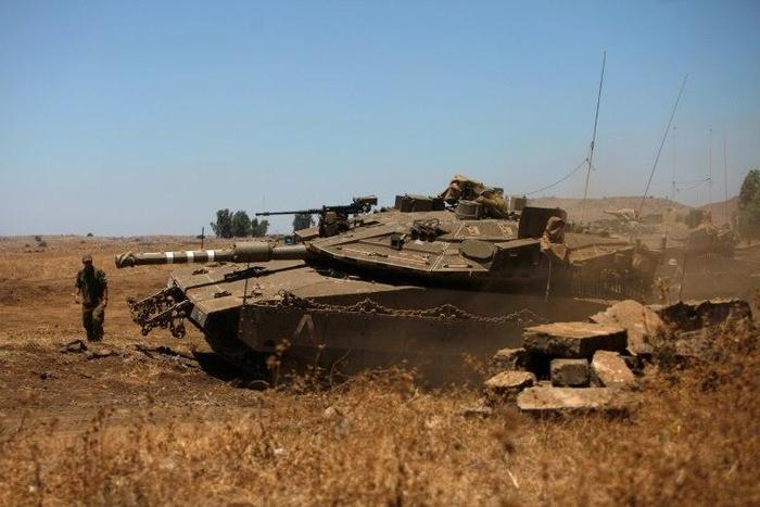 An Israeli soldier directs a Merkava tank stationed in the Israeli-annexed Golan Heights near the Quneitra crossing with Syria