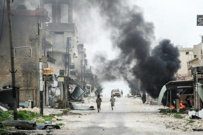 Fighters run past smoke from a burning tyre meant to disrupt warplanes in the Syrian town of Tayyibat al-Imam in the countryside of Aleppo province on March 22, 2017