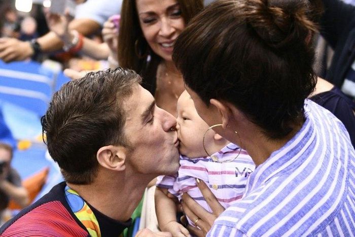 USA's Michael Phelps (L) kisses his son Boomer, held by Nicole Johnson at the Rio Olympics in August 2016