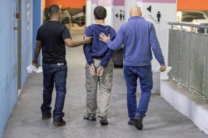 An Israeli-American teenager accused of making dozens of anti-Semitic bomb threats is escorted from an Israeli court in Rishon Lezion on March 23, 2017