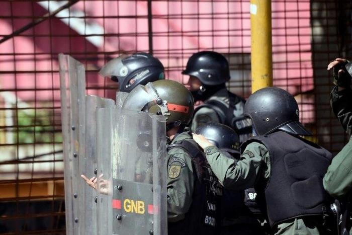 Venezuelan national guard officers in riot gear protect themselves during Friday's protest against President Nicolas Maduro's government