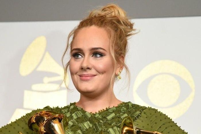 Adele poses in the press room with her five trophies, including the top two Grammys of Album and Record of the Year for her blockbuster hit "Hello" and the album "25"