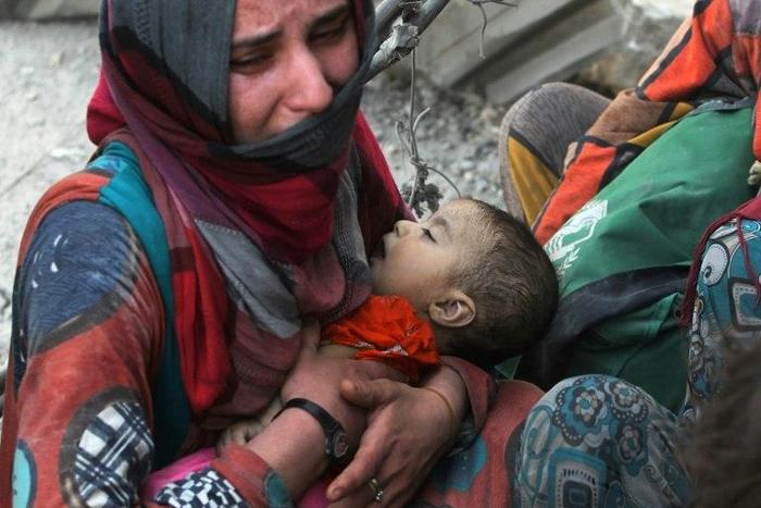 An Iraqi woman carries a child as she flees the Old City of Mosul on July 5, 2017