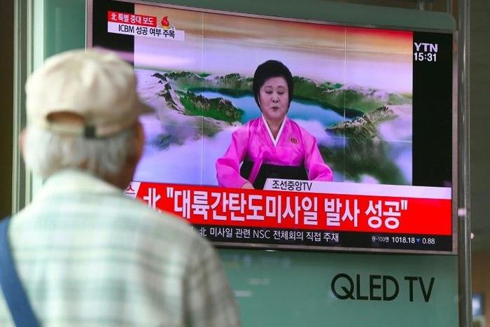 People watch a television news broadcast showing a North Korean announcer reading a statement on the country's new ICBM test, at a railway station in Seoul on July 4, 2017
