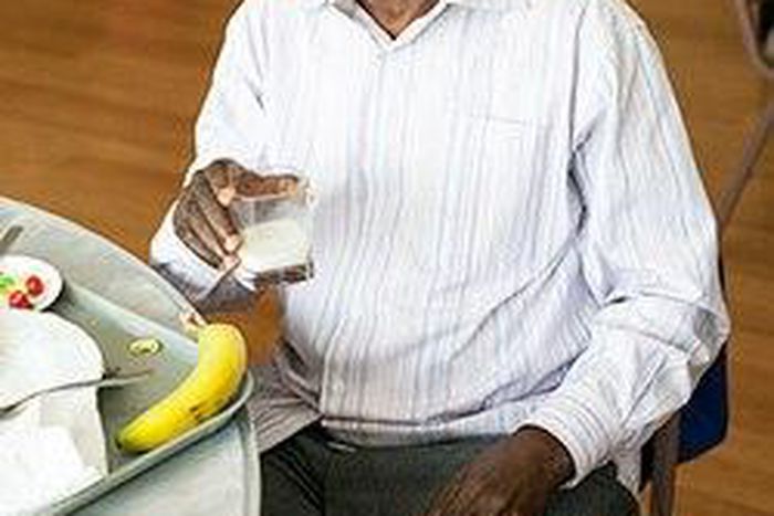 Older African American man making healthy eating choices for his diet with a glass of milk.