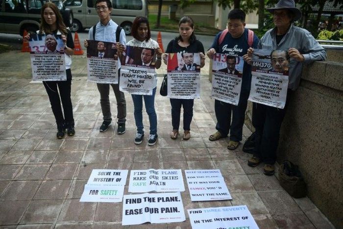 Relatives of passengers missing on Malaysia Airlines MH370 hold placards after a joint press conference of the Ministerial Tripartite Meeting on the search for the missing flight outside Kuala Lumpur on July 22, 2016