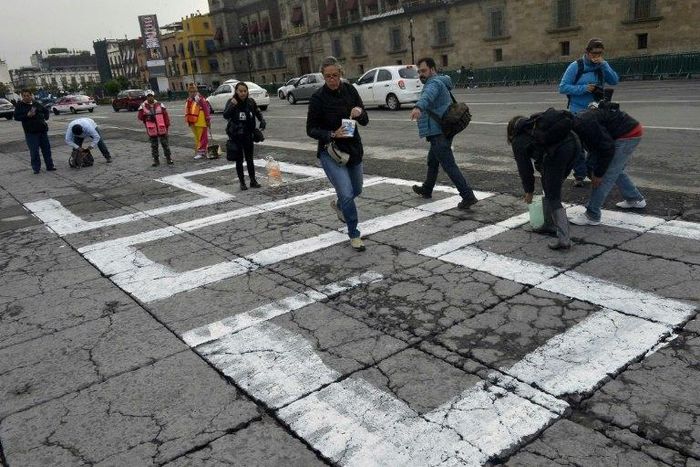 Journalists paint "#sosprensa" (SOS Press) in Mexico City's Zolcalo Square during a protest over the slaying of Salvador Adame, the 6th reporter killed in Mexico this year