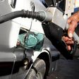 A worker fills the tank of a car at a petrol station.