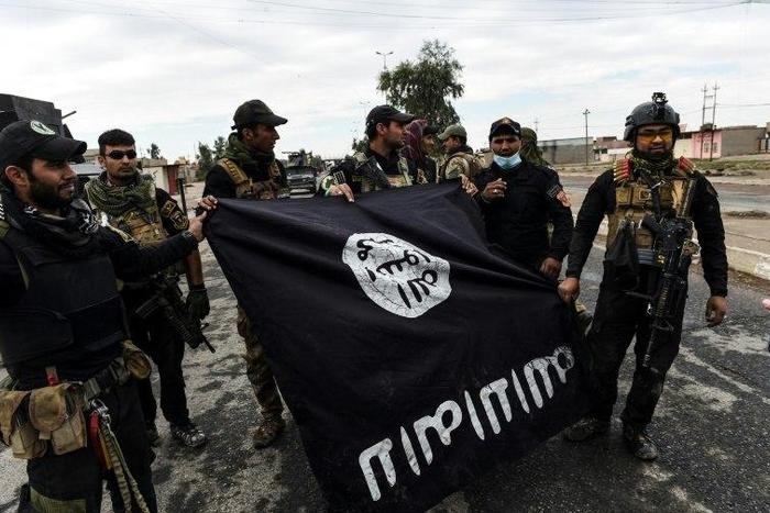 Iraqi soldiers pose with an Islamic State (IS) group flag as they hold a position in the village of Gogjali, a few hundred metres of Mosul's eastern edge, on November 2, 2016