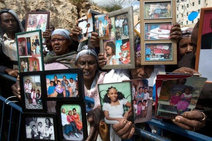 Ethiopian Israelis hold up photographs of relatives in a protest outside the premier's office in Jerusalem on March 20, 2016