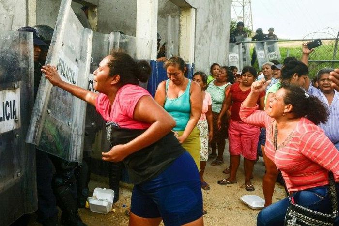 Relatives of inmates struggle with riot police outside Las Cruces prison in Acapulco, following a riot in the facility that left 28 dead and three wounded