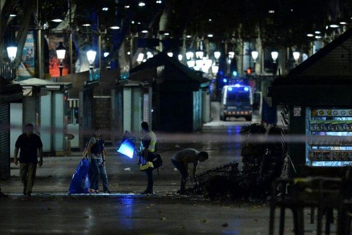 Policemen check the area after towing away the van which ploughed into the crowd, killing at least 13 people and injuring around 100 others on Las Ramblas in Barcelona
