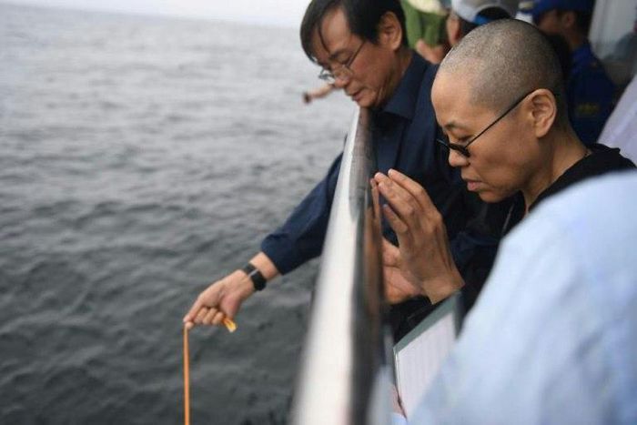 This handout photo provided by the Shenyang Municipal Information Office shows late Nobel laureate Liu Xiaobo's wife Liu Xia praying as they bury Liu's ashes at sea off the coast of Dalian, Liaoning Province, on July 15, 2017