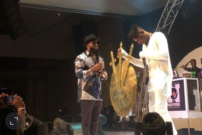 Timaya handing Ycee an artifact