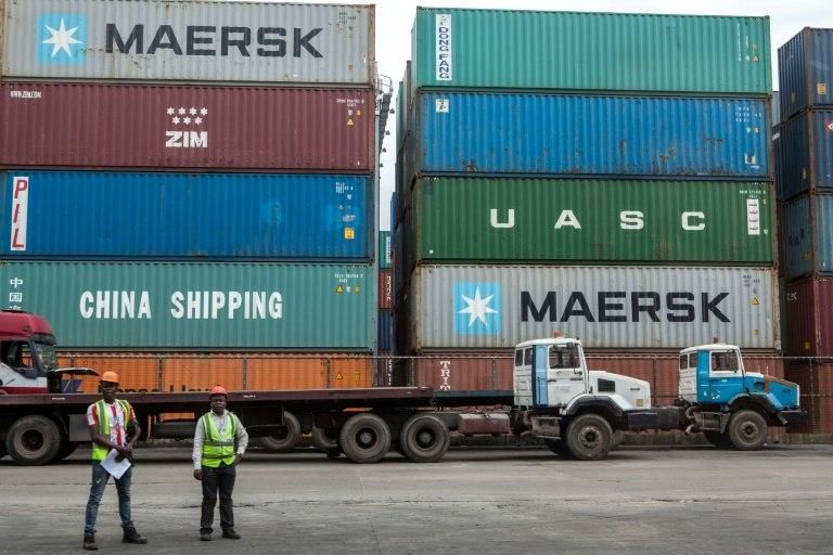 Workers stand next to shipping containers at the Lagos Tin-Can Island container terminal in Apapa, southern Nigeria on October 7, 2015