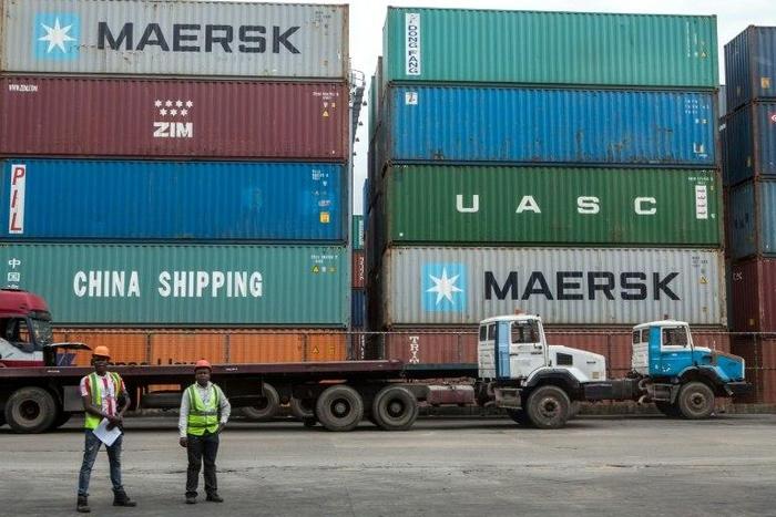 Workers stand next to shipping containers at the Lagos Tin-Can Island container terminal in Apapa, southern Nigeria on October 7, 2015