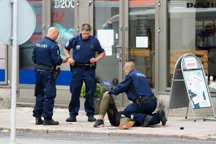Police officers detain the Moroccan suspect who was shot in the leg, in the Finnish city of Turku after a stabbing spree that left two people dead.