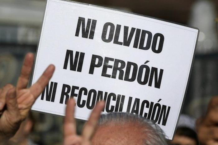 A demonstrator holds a sign reading in Spanish "Neither forget nor forgive, nor reconciliation", during the Madres de Plaza de Mayo human rights group's weekly demonstration at the Plaza de Mayo square in Buenos Aires on May 4, 2017