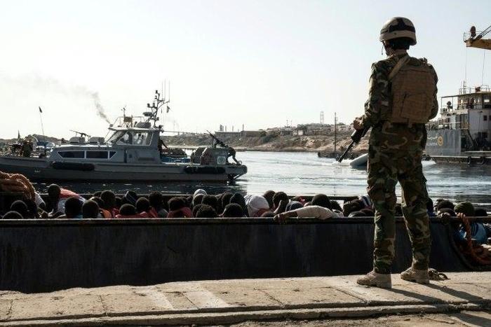 A Libyan coastguard watches on as illegal immigrants are brought to shore in a dinghy during a rescue on June 27, 2017