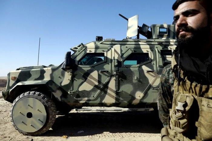 A fighter from the Syrian Democratic Forces, stands next to a military vehicle supplied by the US-led coalition, as advance towards Syria's Raqa on February 3, 2017