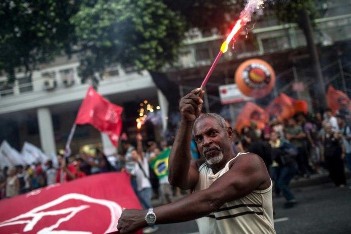 A protester holds fireworks during a demonstration against the Brazilian government's social welfare reform bill in Rio de Janeiro, on March 15, 2017
