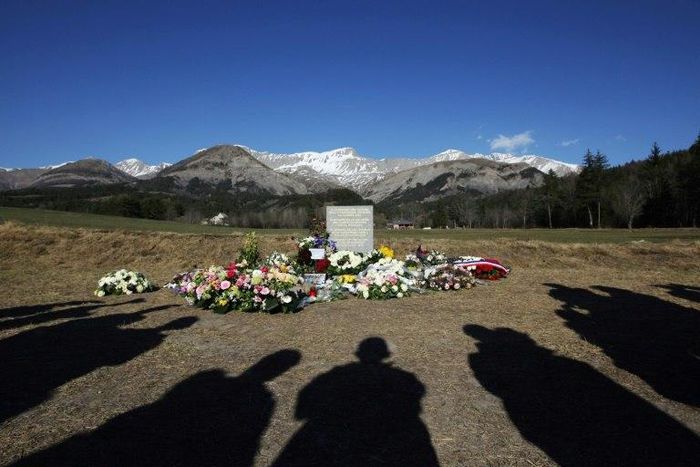 This file photo taken on April 6, 2015 shows people's shadows as they stand near a stela commemorating the victims of the March 24 Germanwings Airbus A320 crash in the village of Le Vernet, southeastern France, after a ceremony with victims' relatives.