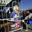 Anti-government activists carry a mock jail containing a cardboard cut-out of South Korea's President Park Geun-Hye of Park in Seoul on March 10, 2017 after the Constitutional Court upheld her impeachment
