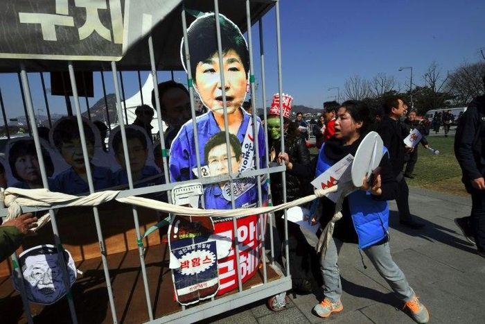 Anti-government activists carry a mock jail containing a cardboard cut-out of South Korea's President Park Geun-Hye of Park in Seoul on March 10, 2017 after the Constitutional Court upheld her impeachment